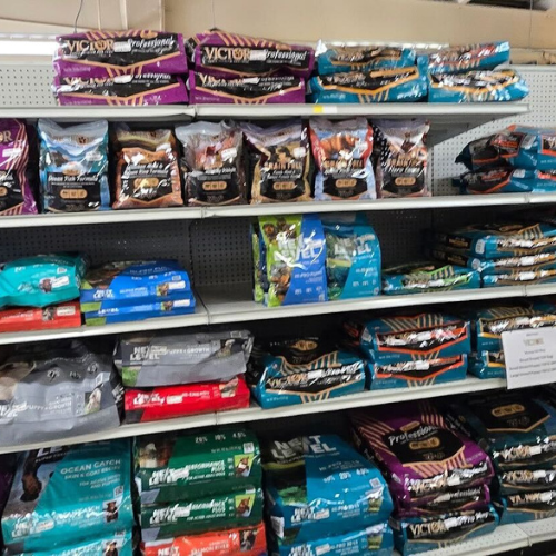 Shelves filled with various colorful bags of pet food, neatly arranged. A mix of brands and flavors create a vibrant, organized display.
